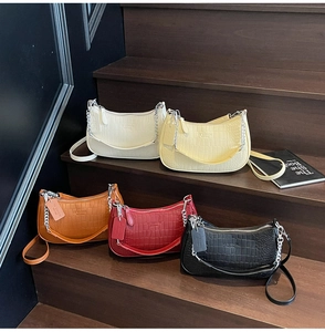 Detail view of five colored crocodile pattern baguette bags with silver chain ornaments