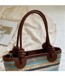 Close-up of a colorful woven straw bucket bag with brown leather handles and knot details