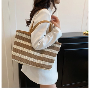 Dettaglio di una grande borsa tote intrecciata a righe con tracolle in pelle marrone su modella