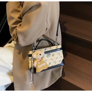 Close-up of stylish bear pattern crossbody bag with a cute plush bear charm accessory