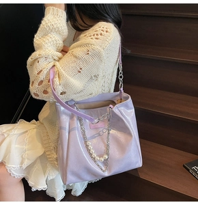 Detail of light purple patent leather tote bag with elegant pearl and silver chain strap