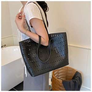 Detail of black laser-cut perforated tote bag with geometric patterns for women