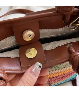 Close-up of golden magnetic clasp on vintage brown leather and multi-color woven straw bag