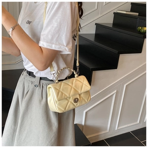 Detail of quilted beige crossbody bag with silver rotating lock and chain strap