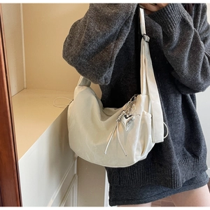 Detail of minimalist beige oversized crossbody bag with silver heart charm and wide strap