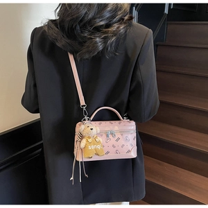 Pink box crossbody bag with bear print pattern and cute plush charm on model