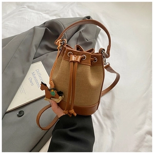 Détail du sac seau en toile avec bordure en cuir marron, cordon et breloque poney