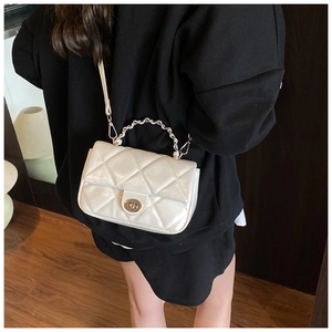 Close-up of white quilted crossbody bag with metal twist lock and woven leather chain handle