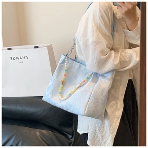 Detail of light blue floral tote bag with colorful beads and silver chain straps