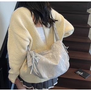 Detail of grey hobo shoulder bag with metallic wrinkled texture and heart pendant