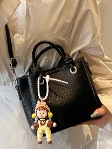 Fashionable black pebbled leather bucket bag with cute cartoon charm and crossbody strap
