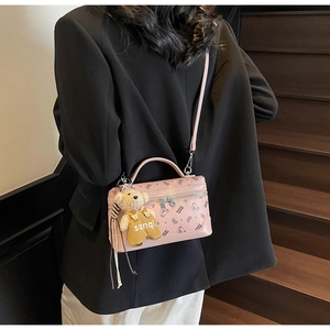 Pink box-shaped crossbody bag featuring a bear print and plush charm on a long strap
