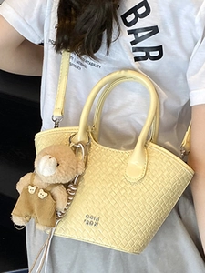 Borsa a secchiello intrecciata giallo chiaro con ciondolo a orsetto e tracolla