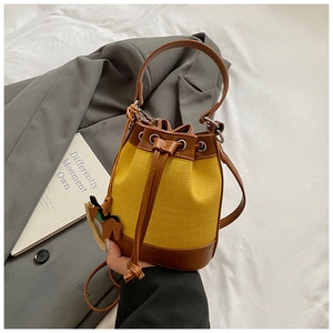 Détail du sac seau tissé jaune avec cordon en cuir et pendentif cheval élégant