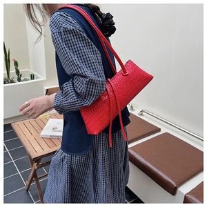 Detail of red woven leather shoulder bag with decorative straps on a lifestyle model
