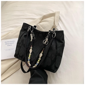 Close-up of black heart-patterned tote bag with colorful beaded charm accessory
