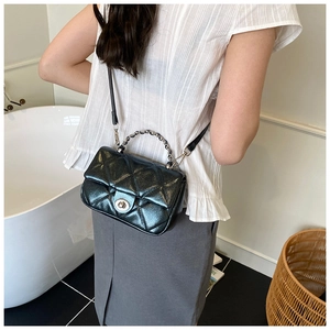 Detailed view of black metallic quilted crossbody bag with silver chain strap and twist lock