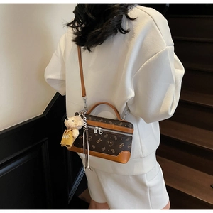 Rear view of model wearing a vintage brown patterned crossbody bag with bear charm