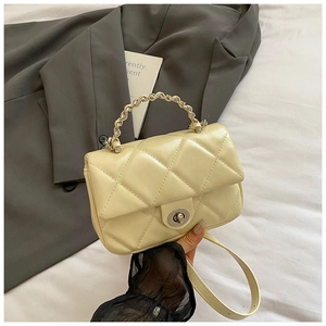Detail of beige quilted crossbody bag with silver chain handle and turn-lock closure