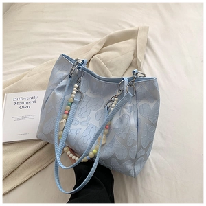 Detail of light blue tote bag featuring embossed heart texture and colorful bead chain