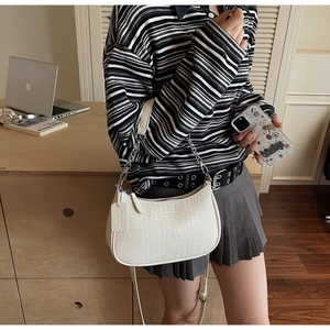 Close-up of white crocodile pattern baguette bag with stylish metal chain shoulder strap