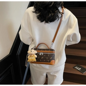 Detail of vintage brown bear patterned crossbody bag with plush charm and leather handle