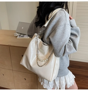 Detail of cream tote bag featuring silver chain and large pearl strap accents