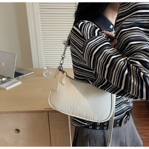 Detail of white crocodile pattern baguette bag with silver chain and IT CHICK logo