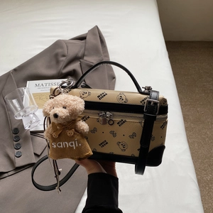 Detail of yellow crossbody bag featuring bear print and cute plush bear charm accessory