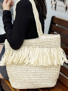 Beige straw tote bag with long tassel detail for beach vacation and summer style