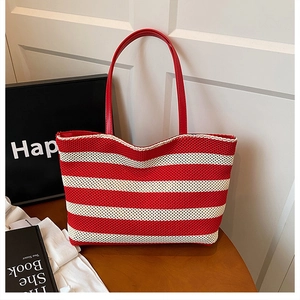 Dettaglio della borsa tote intrecciata a righe bianche e rosse con manici rossi