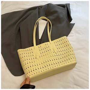 Close-up of laser-cut geometric hollow pattern on light yellow PU leather tote bag