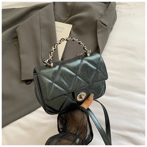 Close-up of black glitter quilted handbag with silver round twist lock and chain strap