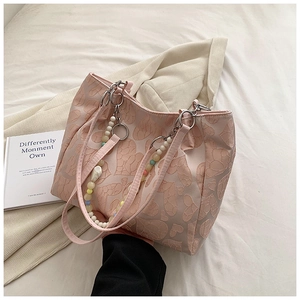 Detail of light pink tote bag featuring heart jacquard texture and beaded charm