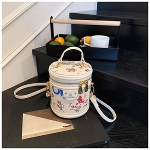 Close-up of white bucket bag with colorful cartoon graffiti and gold hardware accents