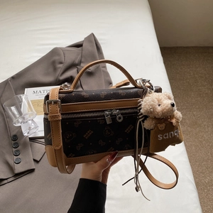 Close-up of vintage brown box bag with bear prints and a soft plush bear charm detail