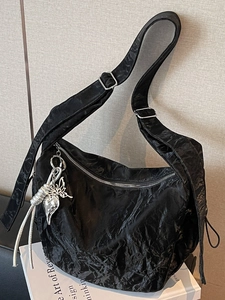 Minimalist black crinkled half moon shoulder bag with oversized silver butterfly pendant