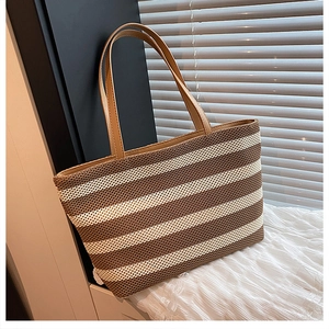 Vista dettagliata della borsa tote tessuta con strisce marroni su sfondo di tessuto bianco
