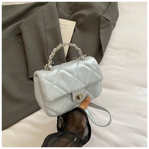 Close-up of light blue quilted crossbody bag with pearl chain handle and silver clasp