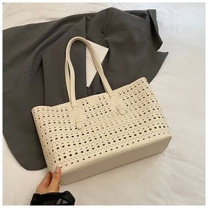 Detailed view of beige hollow-out tote bag featuring premium leather and punch-hole patterns