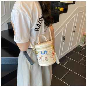 Side view of white bucket bag with colorful graffiti and adjustable shoulder strap