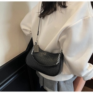 Close-up of black crocodile-embossed baguette bag with silver chain and IT CHICK logo