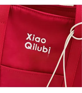 Détail de la broderie de lettres blanches sur le tissu tissé rouge du sac