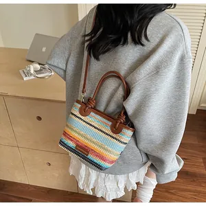 Detail of colorful striped woven crossbody bag with brown leather straps on a model