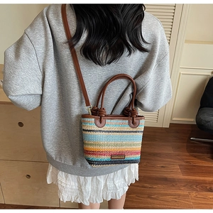 Close-up of colorful striped straw bucket bag with leather handles and metal brand plate