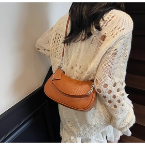 Detail of a brown croc-embossed half-moon bag featuring silver chain and adjustable strap