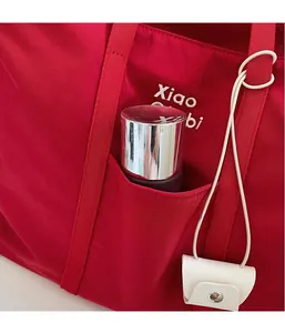 Détail du sac cabas rouge avec poche latérale pratique et broderie blanche élégante