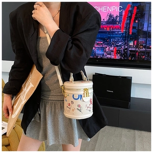 Detailed view of white bucket bag with colorful graffiti art and dual gold zippers