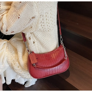 Close-up of red baguette bag with crocodile pattern and silver chain detail on bag