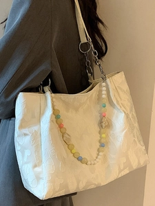 Chic white tote bag with heart embossed texture and colorful beaded chain strap detail